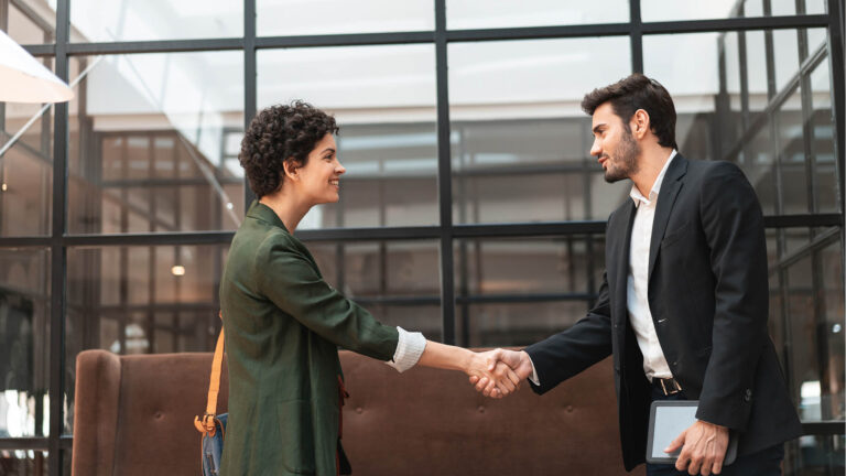 Deux professionnels de la CCI Nice Côte d’Azur se serrant la main dans un bureau moderne, symbolisant un partenariat international.