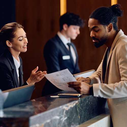 Accueil d’un client à la réception d’un hôtel, illustrant les métiers du secteur du tourisme.