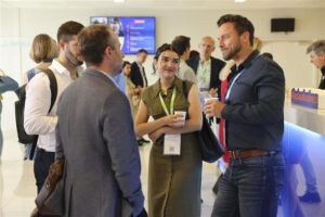 Un groupe de personnes discutant lors d'un événement de réseautage professionnel, certaines tenant des tasses et portant des badges.